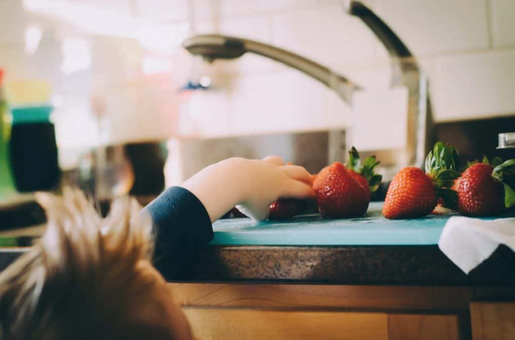 kid reaching for strawberries fruit