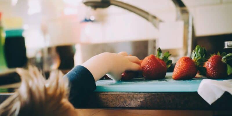 kid reaching for strawberries fruit