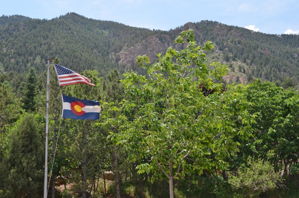 USA Flag and Colorado flag flying on mountain