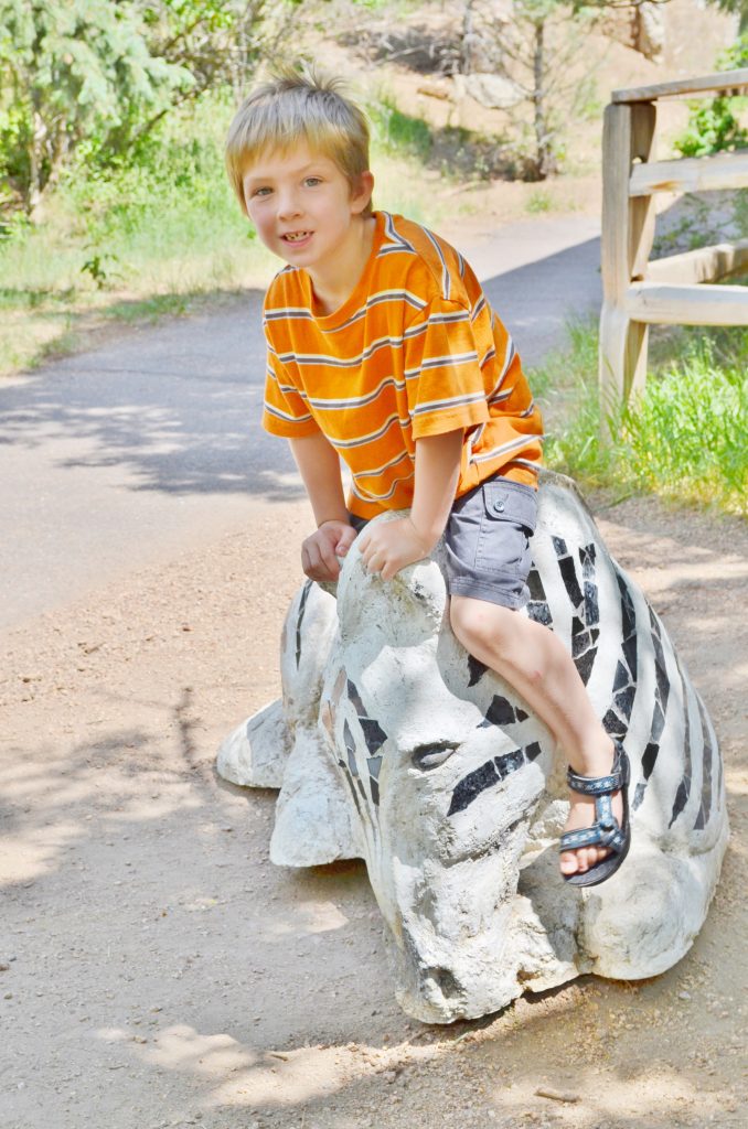 boy sitting on a zoo animal statue