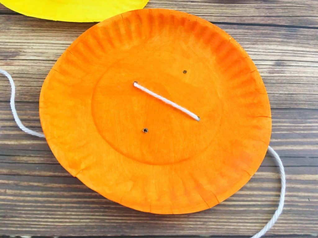 orange paper plate with white string craft
