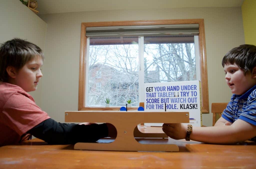 two boys playing Klask magnetic game