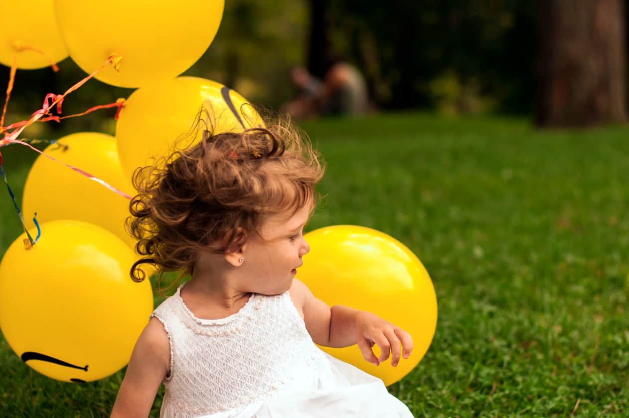 toddler girl with yellow balloons