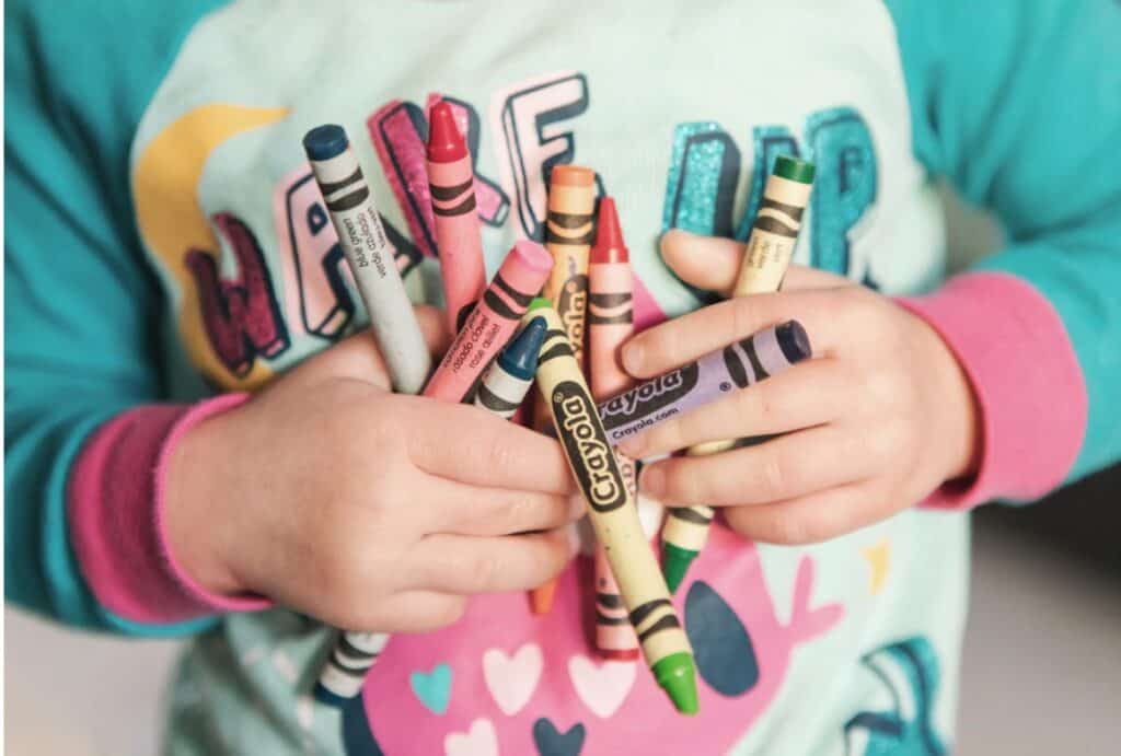 child holding crayons