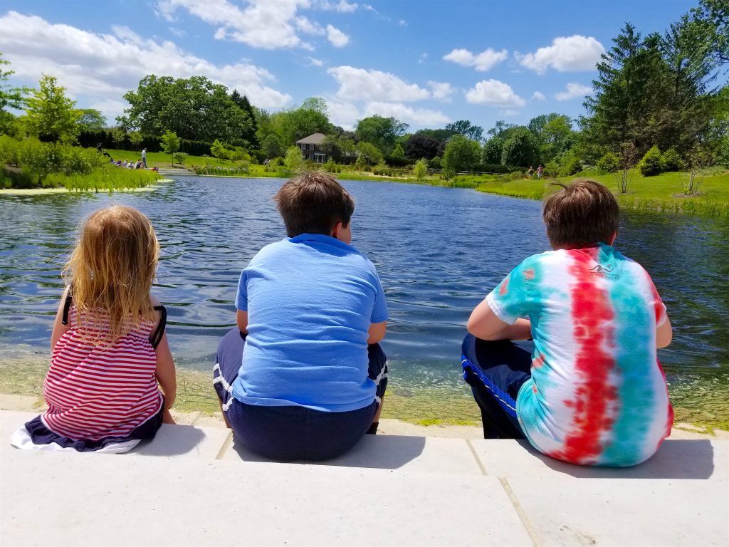 3 kids sitting in front of lake