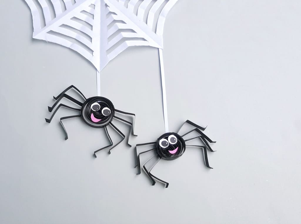 two paper quilled spiders on web