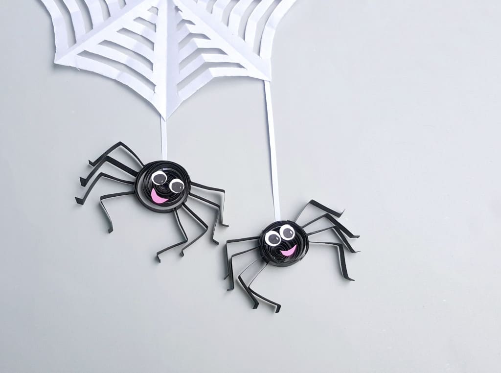 two paper quilled spiders on web