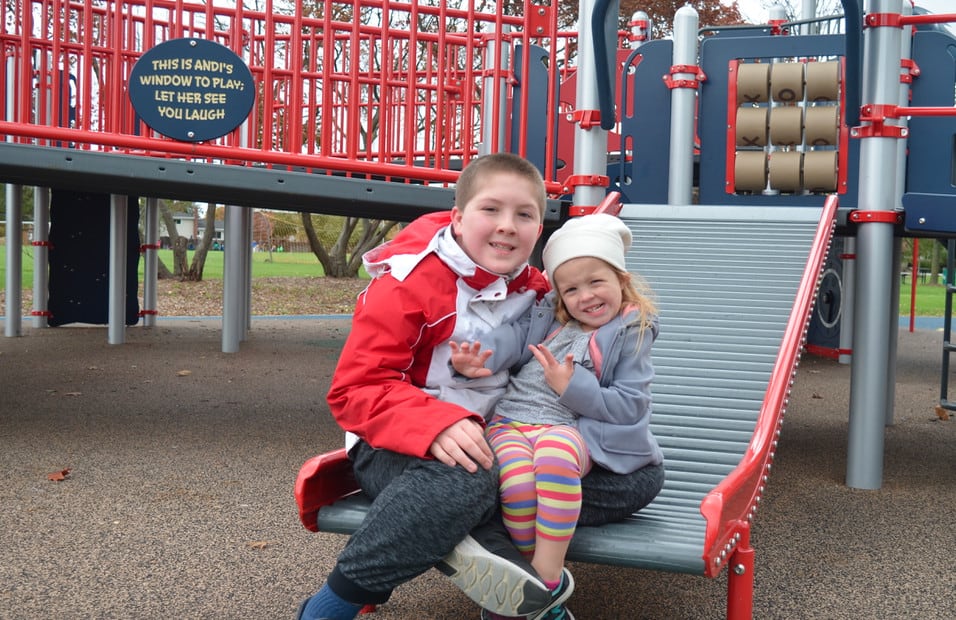 brother and sister at playground on roller slide