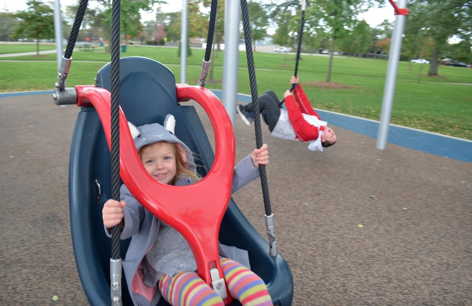 little girl in handicap swing on inclusive playground