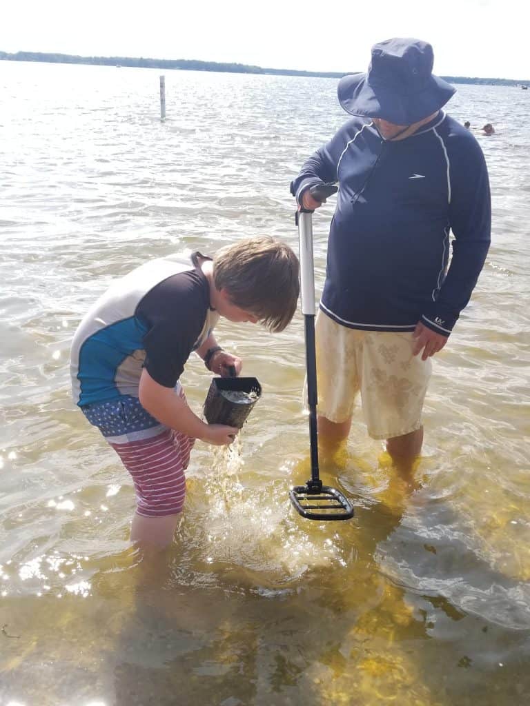 father and son metal detecting on the beach