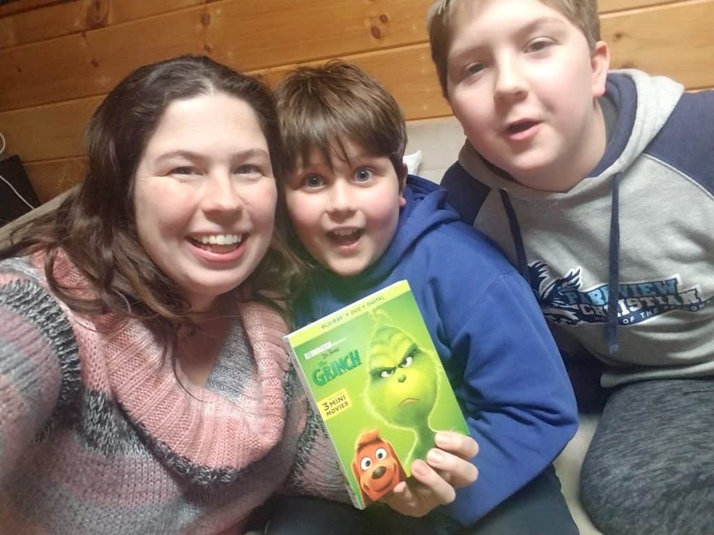 mom with two boys family holding The Grinch movie