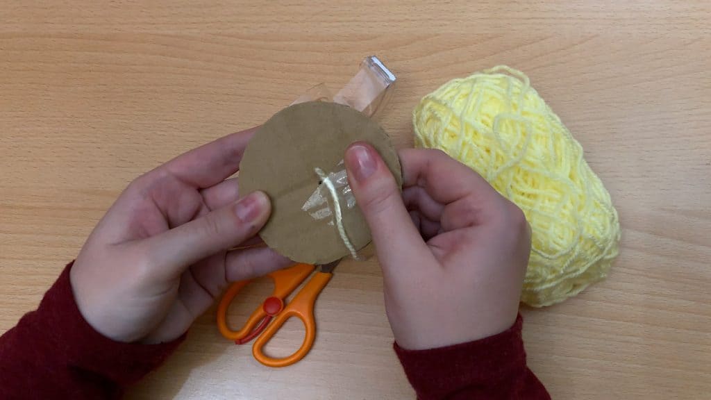 taping yellow yarn on cardboard circle