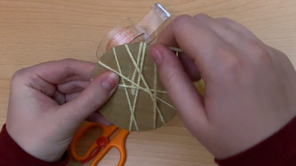 wrapping yellow yarn string around circle