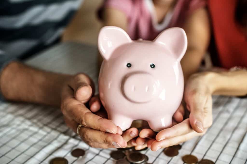 mom dad child hands holding piggy bank