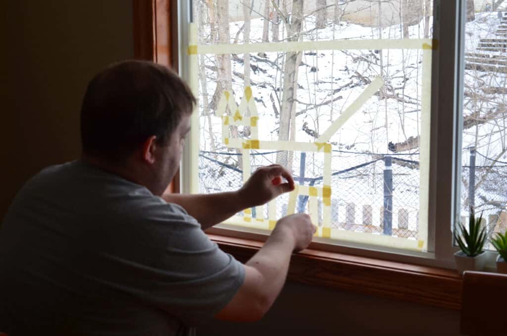 man putting tape on window