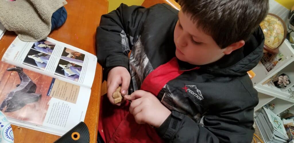 boy whittling wood whale