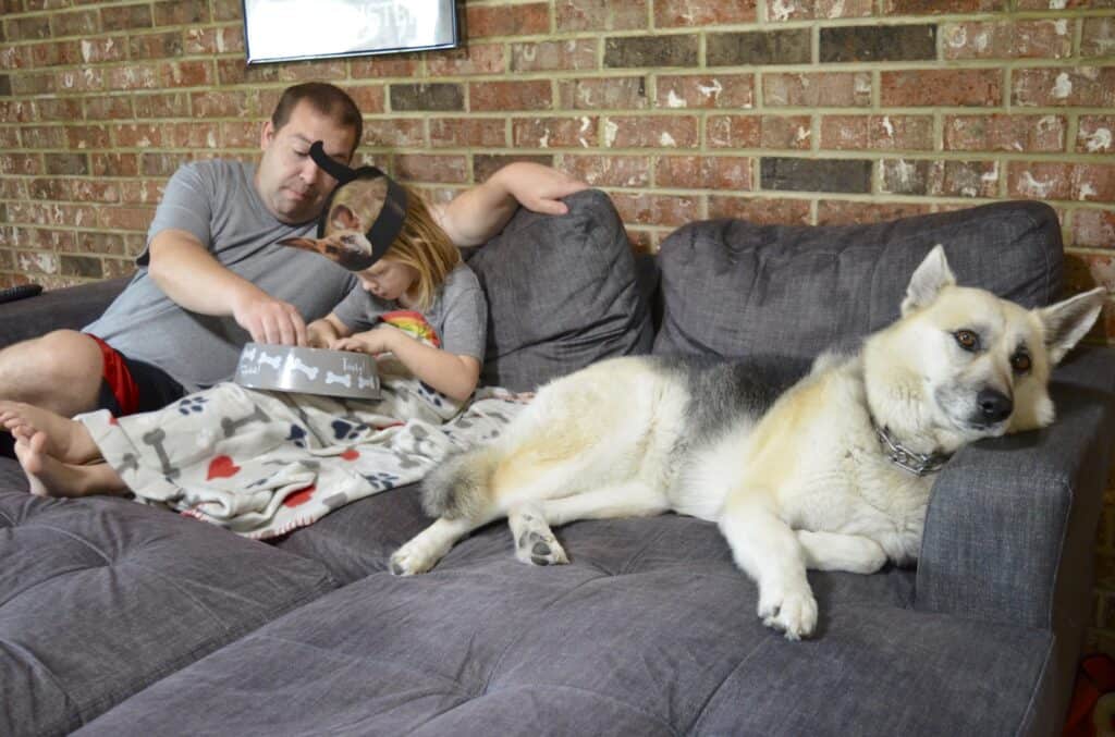 dad and daughter with dog watching tv