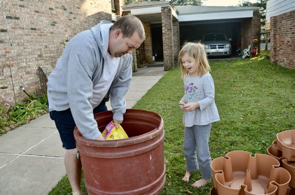 little girl pouring dirt with dad