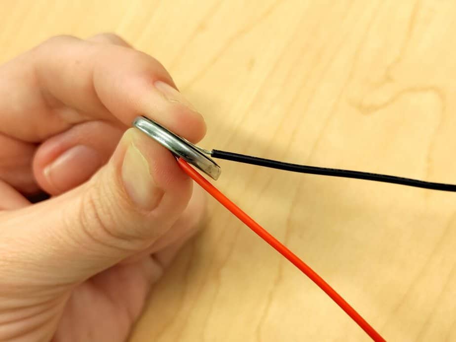 taping wires on both sides of a button battery